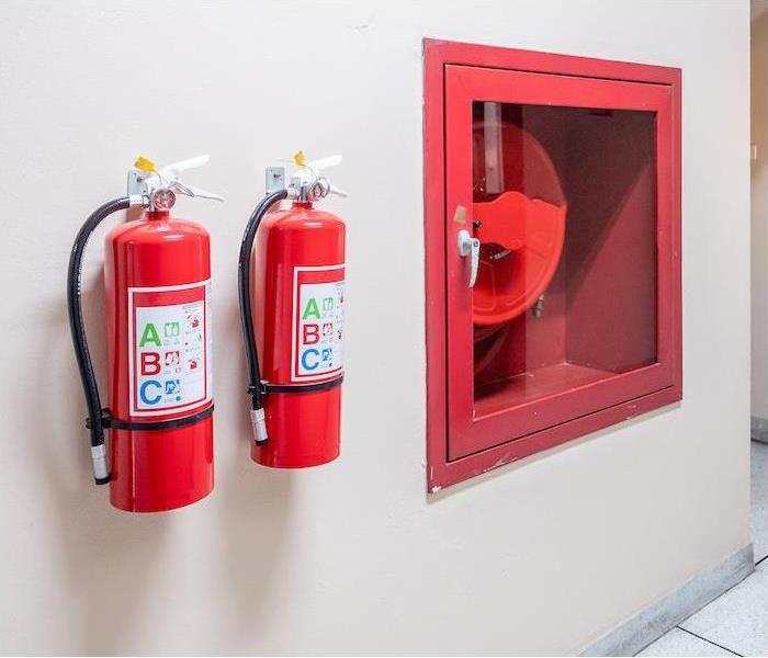 img src =”extinguisher” alt = "two fire extinguisher hanging on a tan interior wall  ” >